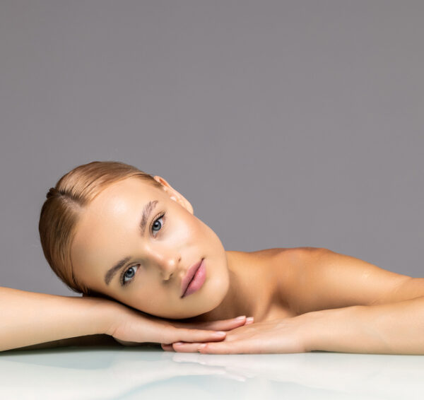 Healthy skin young woman beautiful face close up over gray background